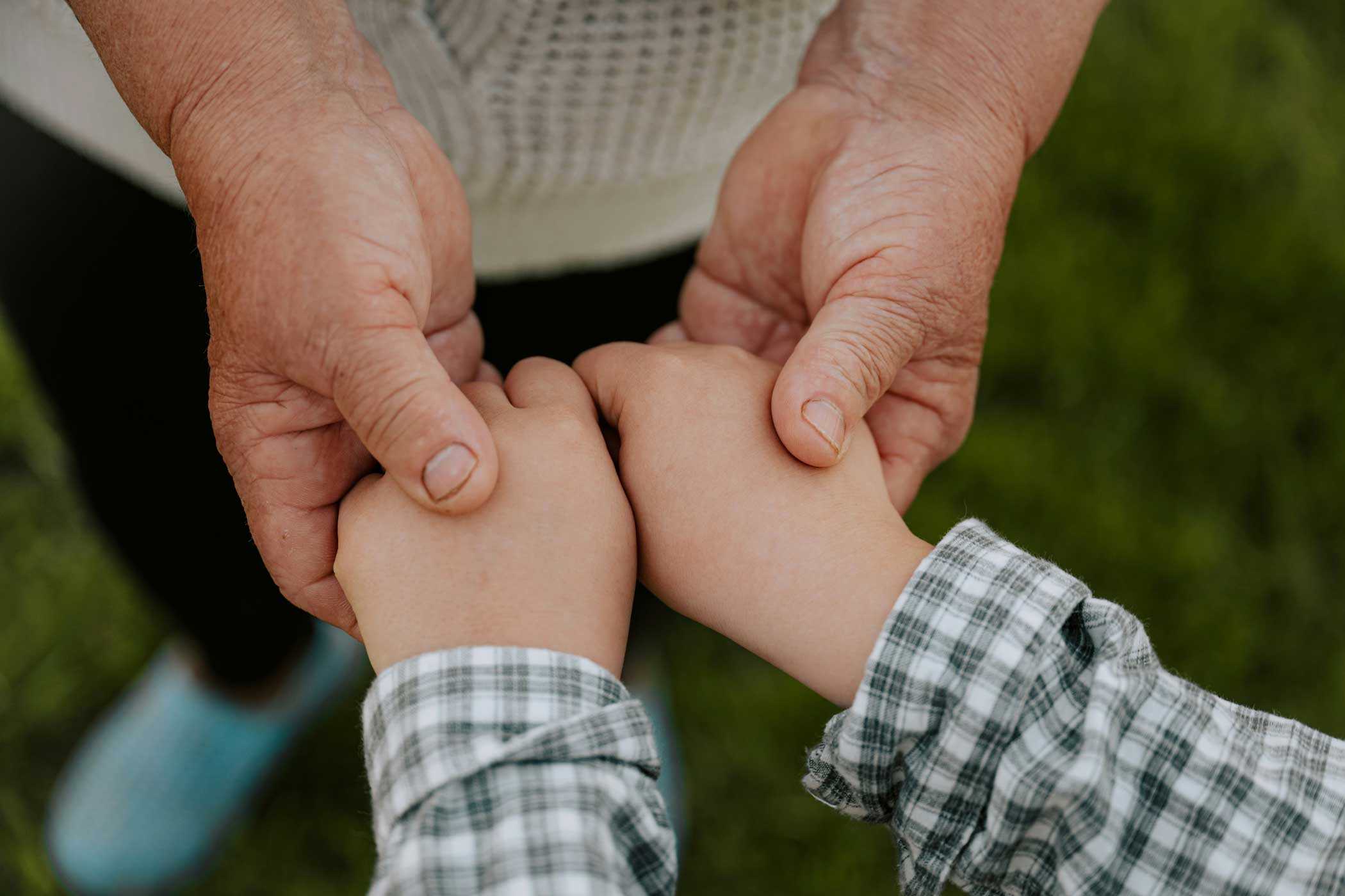 An older person’s hands holding a child’s hands